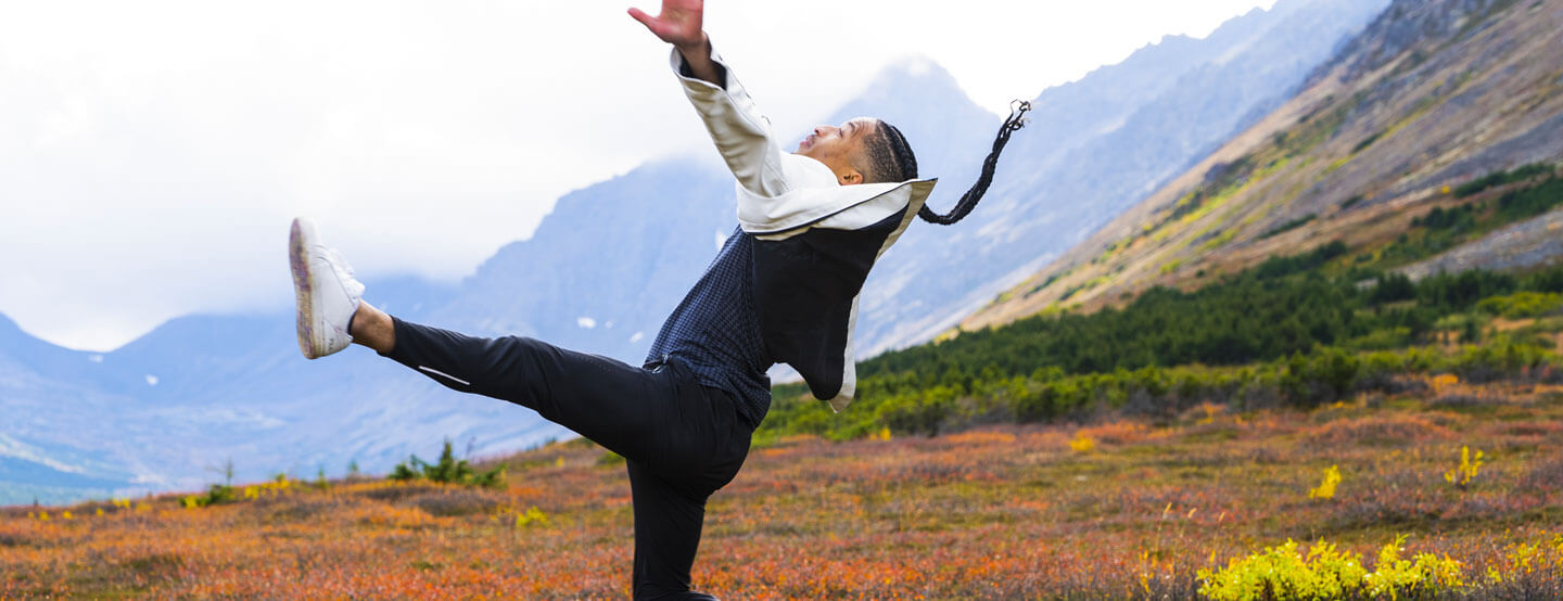 Young male dancer with Alaskan mountains behind him.