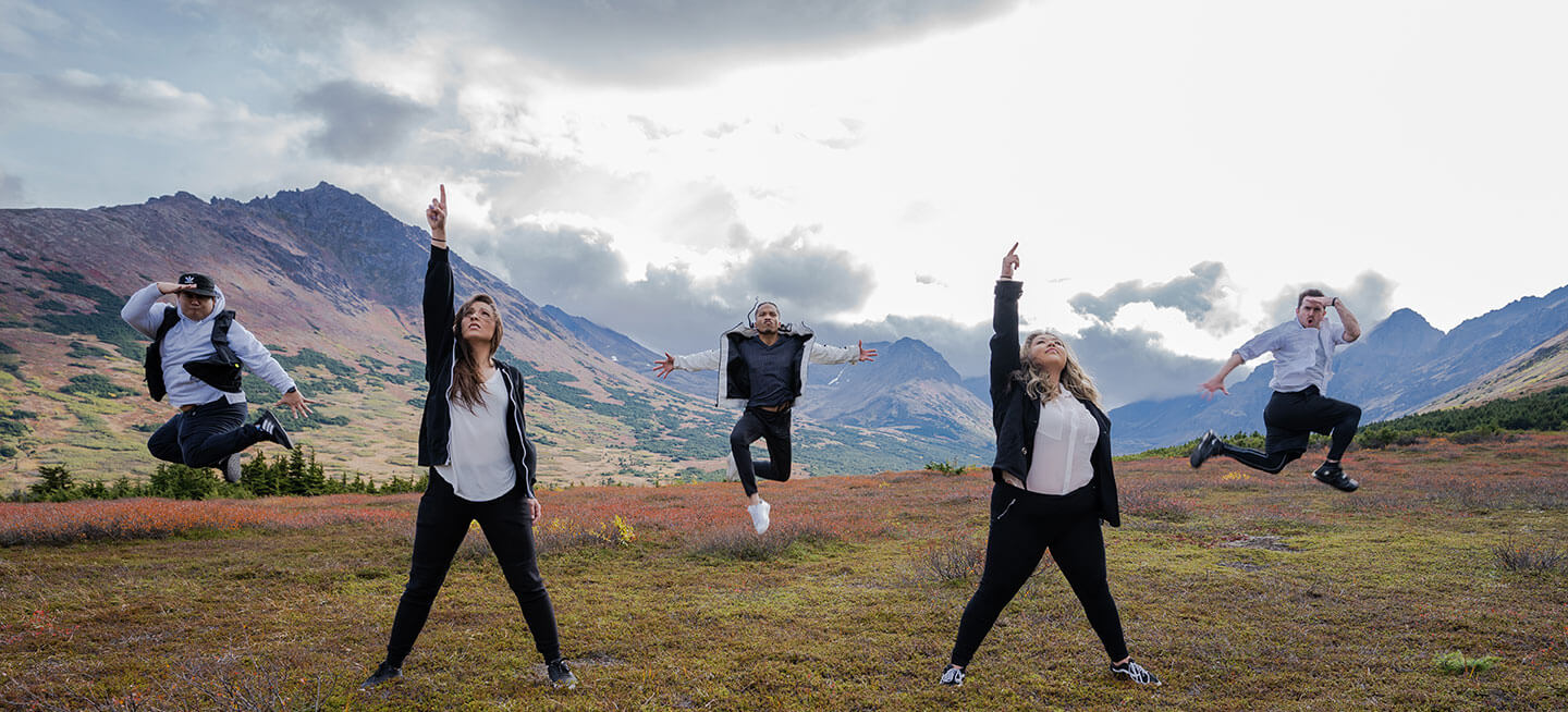 Multiple dancers on top of beautiful Alaskan mountains.