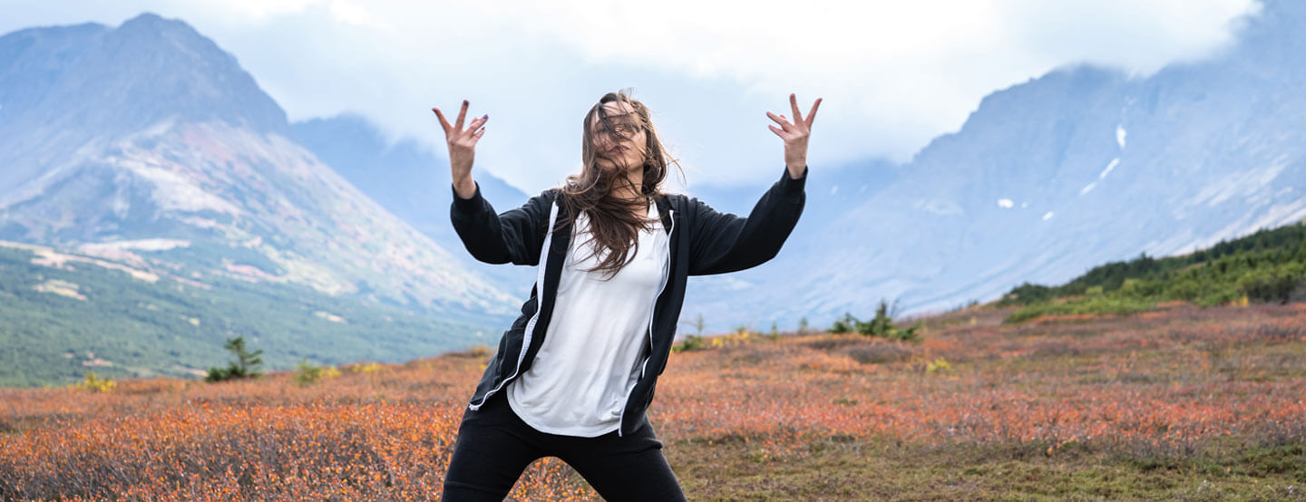 Woman dances with Alaska mountains behind.